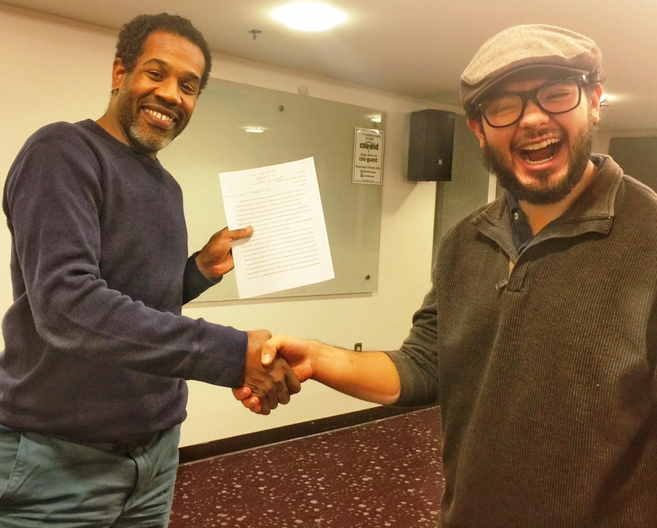 Cesar Ita gives Gregory Pardlo a copy of his midterm, an analysis of Pardlo's Pulitzer Prize-winning book of poetry, Digest
