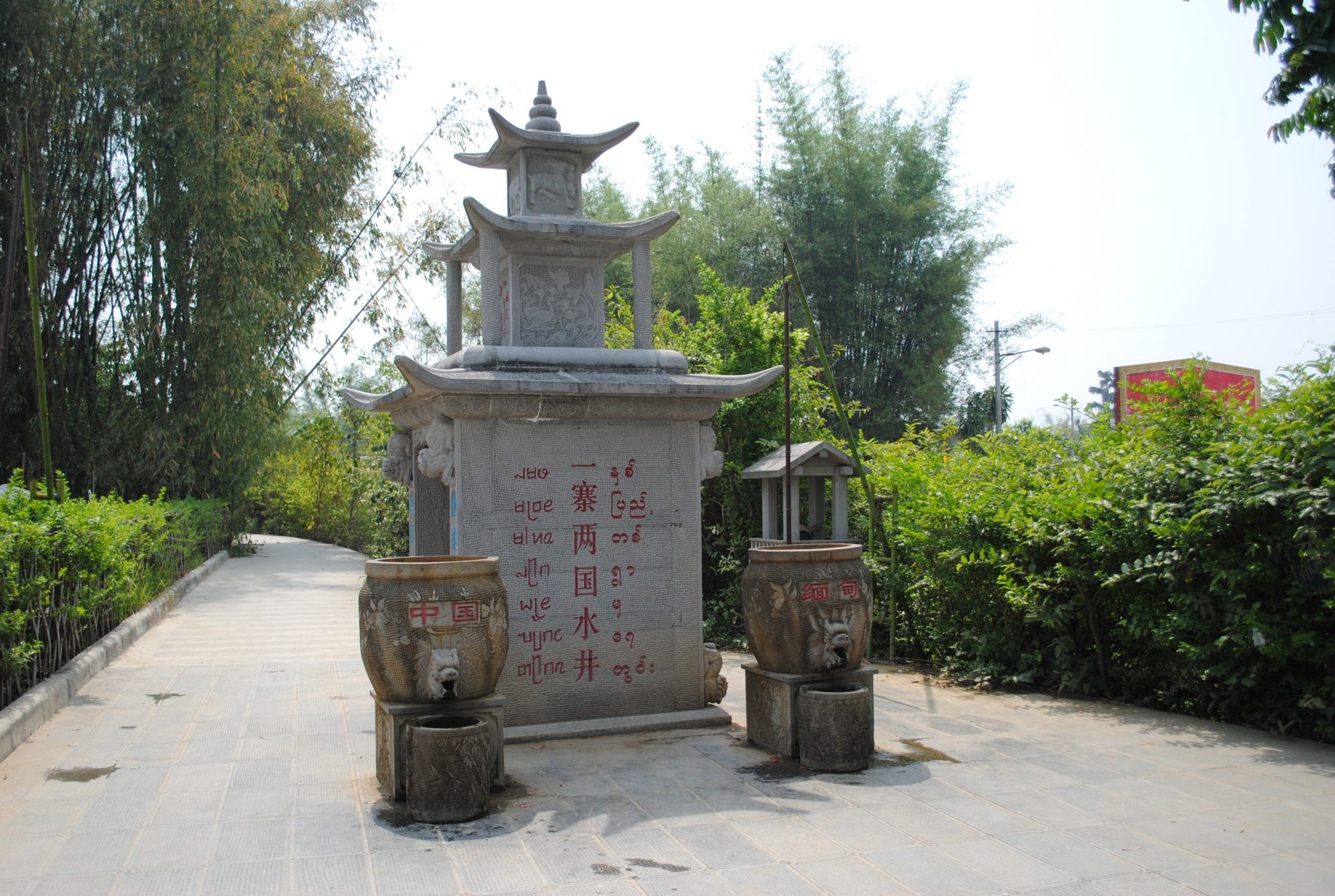 The vertical words in Chinese say: Wells (as in well for water) of the One Village Two Countries. The well on the left says "China" and the well on the right says "Myanmar." Photograph taken by Jiajia Wang.