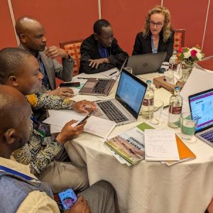 Kathleen Galvin sits at a table with Kenya forest managers to demo the new app