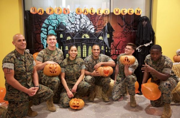 Justin Frigault and his fellow service members in marine corps combat utility uniform, holding pumpkins at a Halloween function