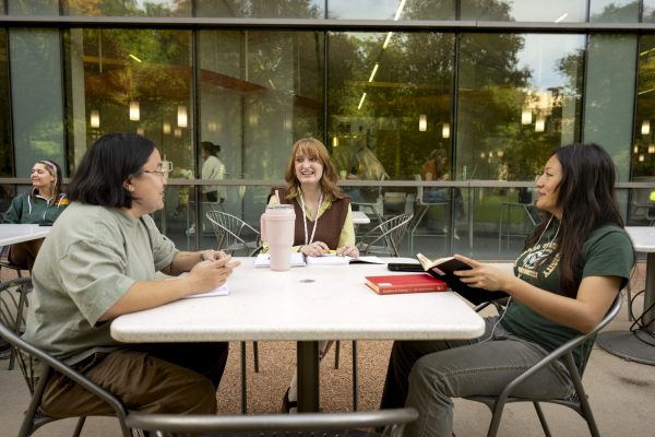 Three students in conversation at a table outside the BSB on the CSU campus